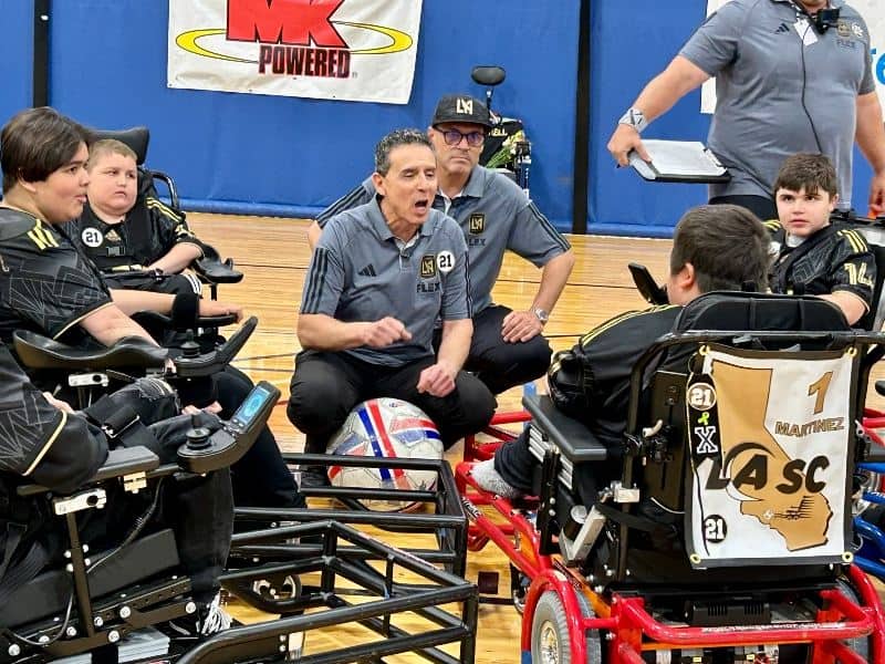 Coach encouraging power soccer players during a break in the game.