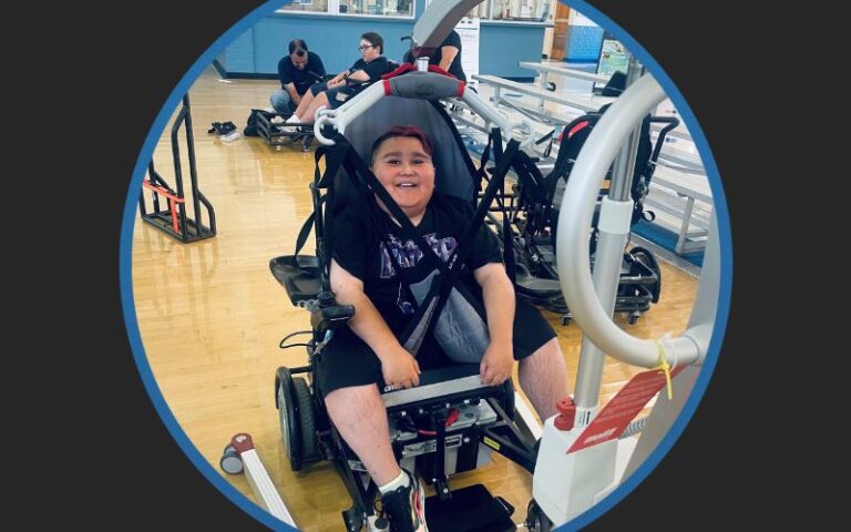Young male with Duchenne Muscular Dystrophy using a assistive lift device that was donated by Walking Strong