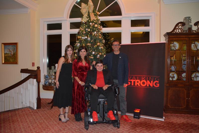 The Llauro family posing in front of a Christmas tree and Walking Strong banner at A Night of Cocktails & Conversation