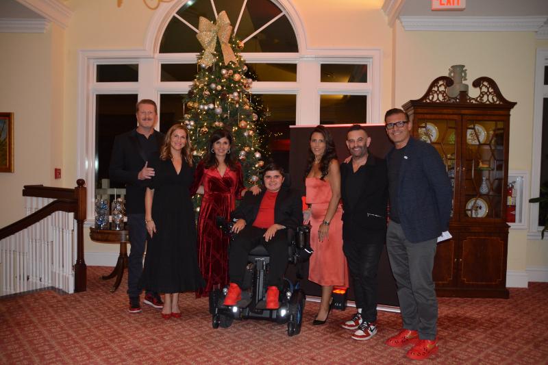 Alex, his family and friends in a group photo in front of a Christmas tree at A Night of Cocktails & Conversation