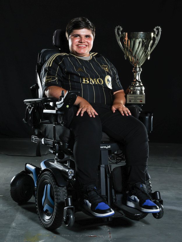 Alex in his wheelchair posing with a trophy