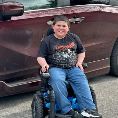 Young boy with Duchenne MD next his van